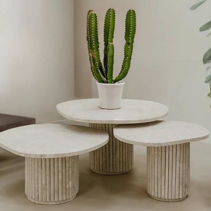 Lot de trois tables basses en travertin naturel avec pieds rainurés, au design sculptural et organique.