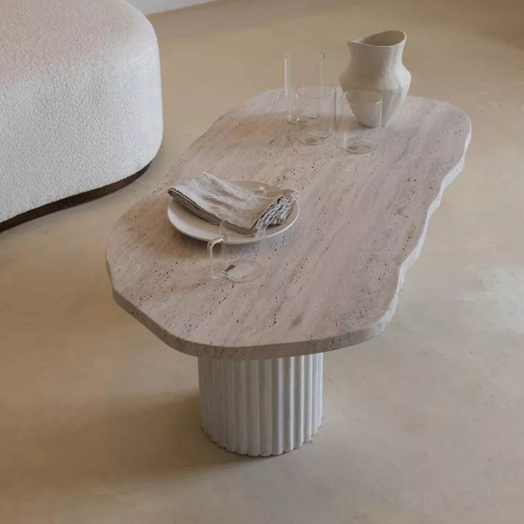 Table basse asymétrique en travertin avec pied cannelé, au design organique et sculptural.
