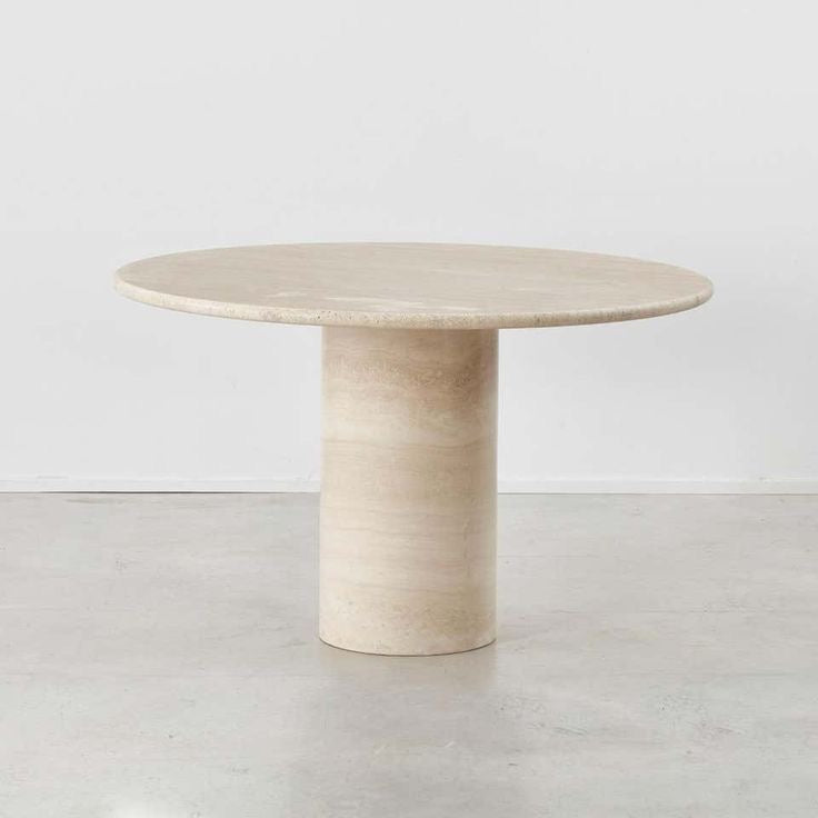 Table ronde en travertin naturel avec pied cylindrique, design épuré et intemporel.