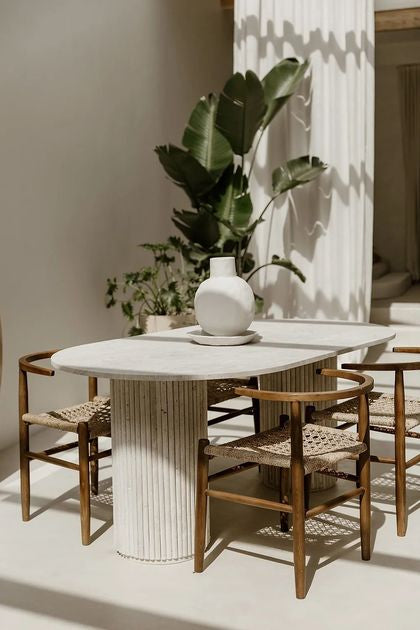 Table en travertin avec double pied baguette dans un intérieur épuré et chaleureux.