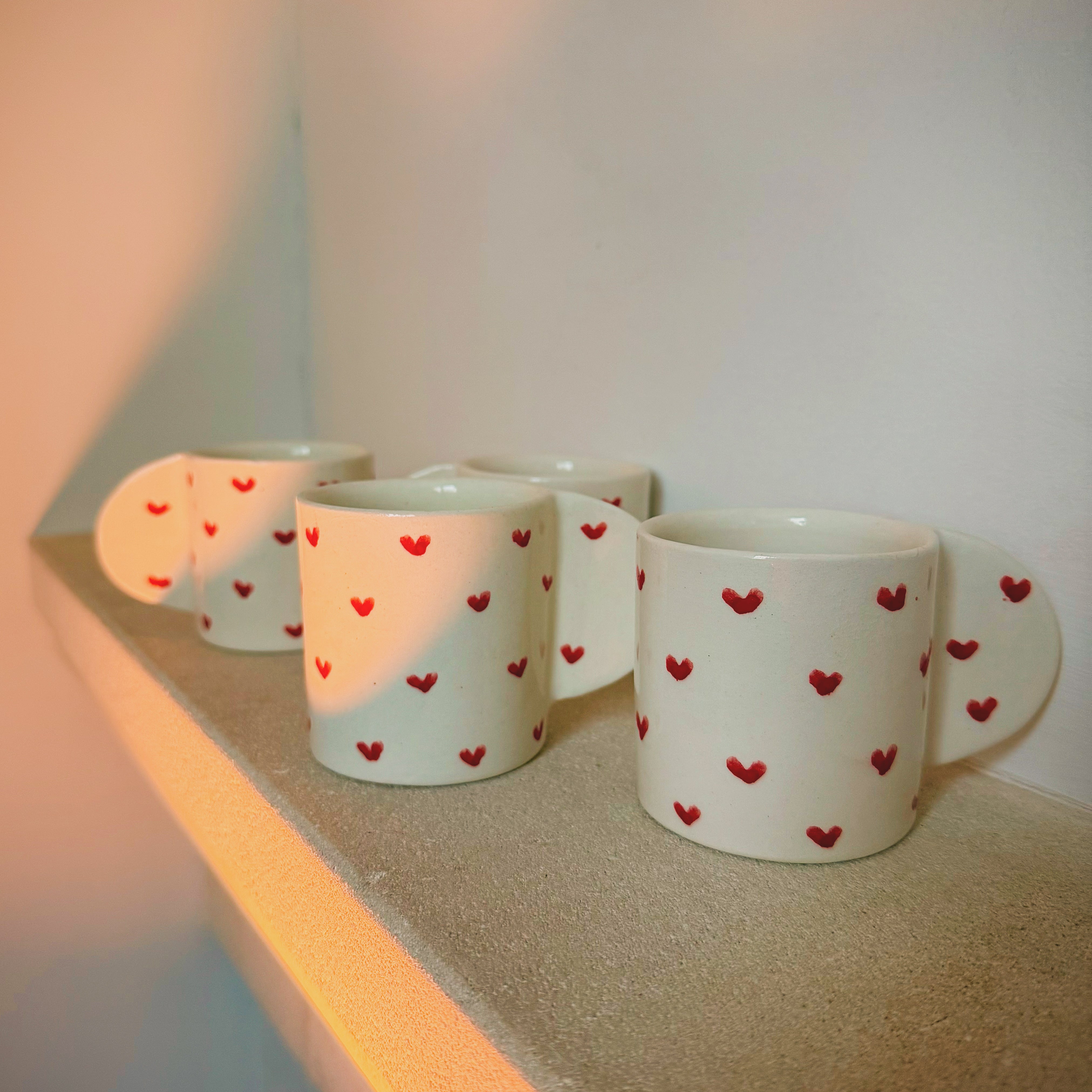 Lot de quatre tasses en porcelaine artisanale avec motif cœur rouge, design romantique et délicat.