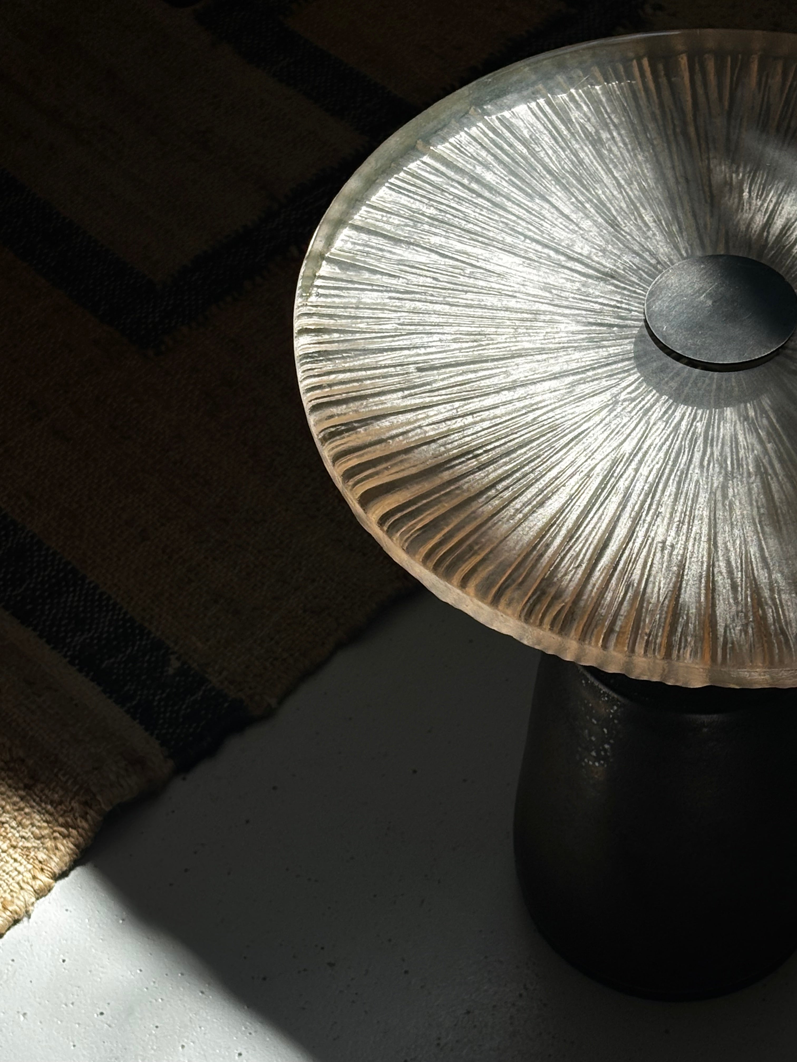 Détail du plateau en verre coulé façonné à la main sur guéridon artisanal en grès et acier patiné.