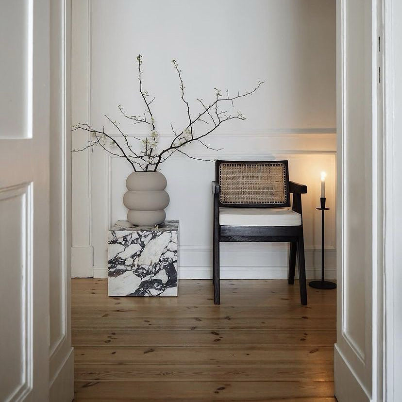 Table d’appoint en marbre Calacatta Viola dans une décoration intérieure élégante avec fauteuil design et vase contemporain