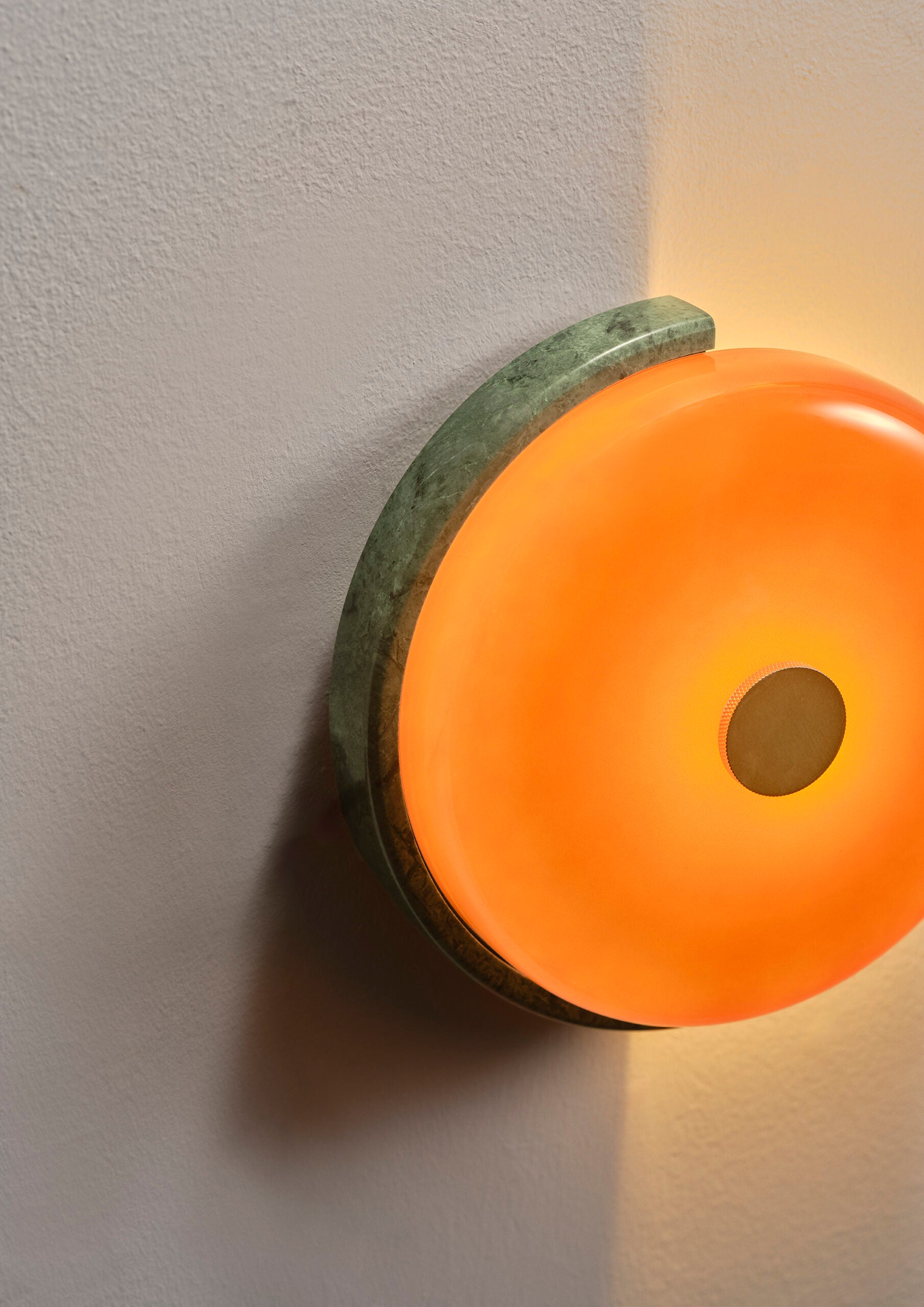 Cette applique murale à poser en intérieur est sculptée à la main dans du marbre brut et coiffée d’un globe soufflé artisanalement.